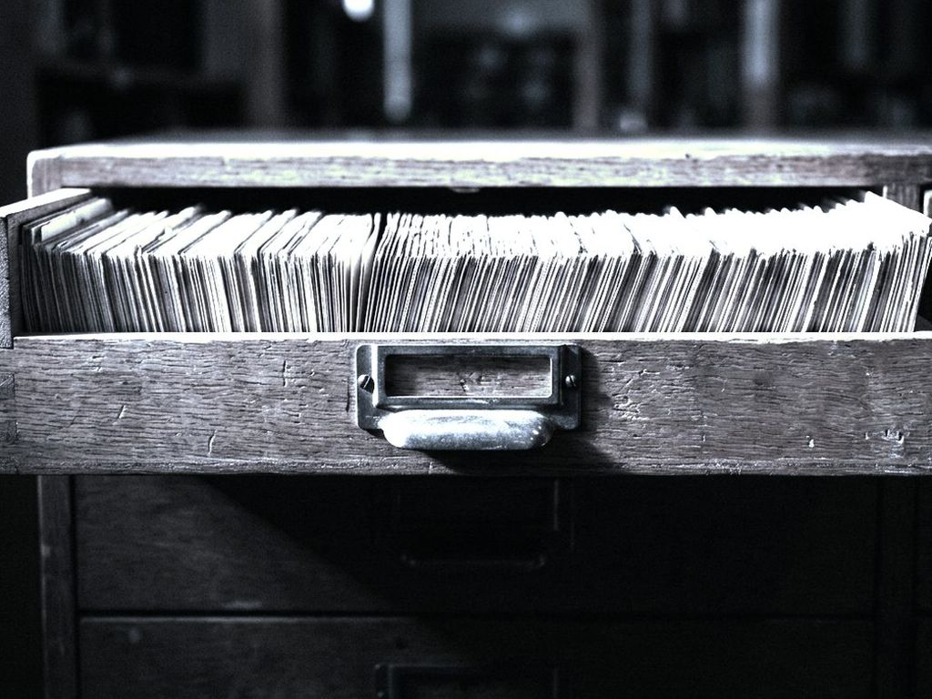 A library card catalogue drawer pulled fully open, hundreds of index cards packed edge to edge.