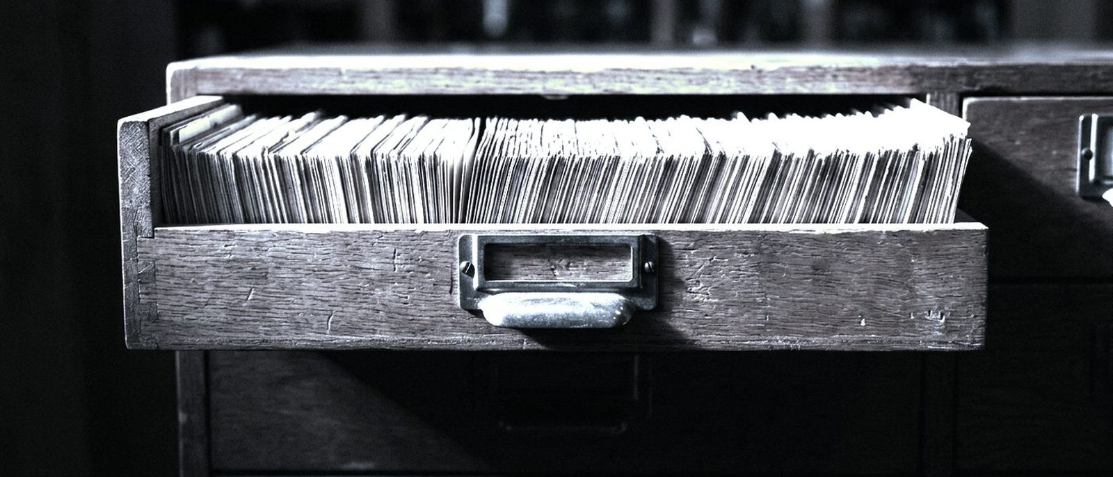A library card catalogue drawer pulled fully open, hundreds of index cards packed edge to edge.