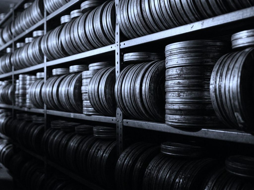 Metal film reel canisters stacked in long rows along archive shelves.