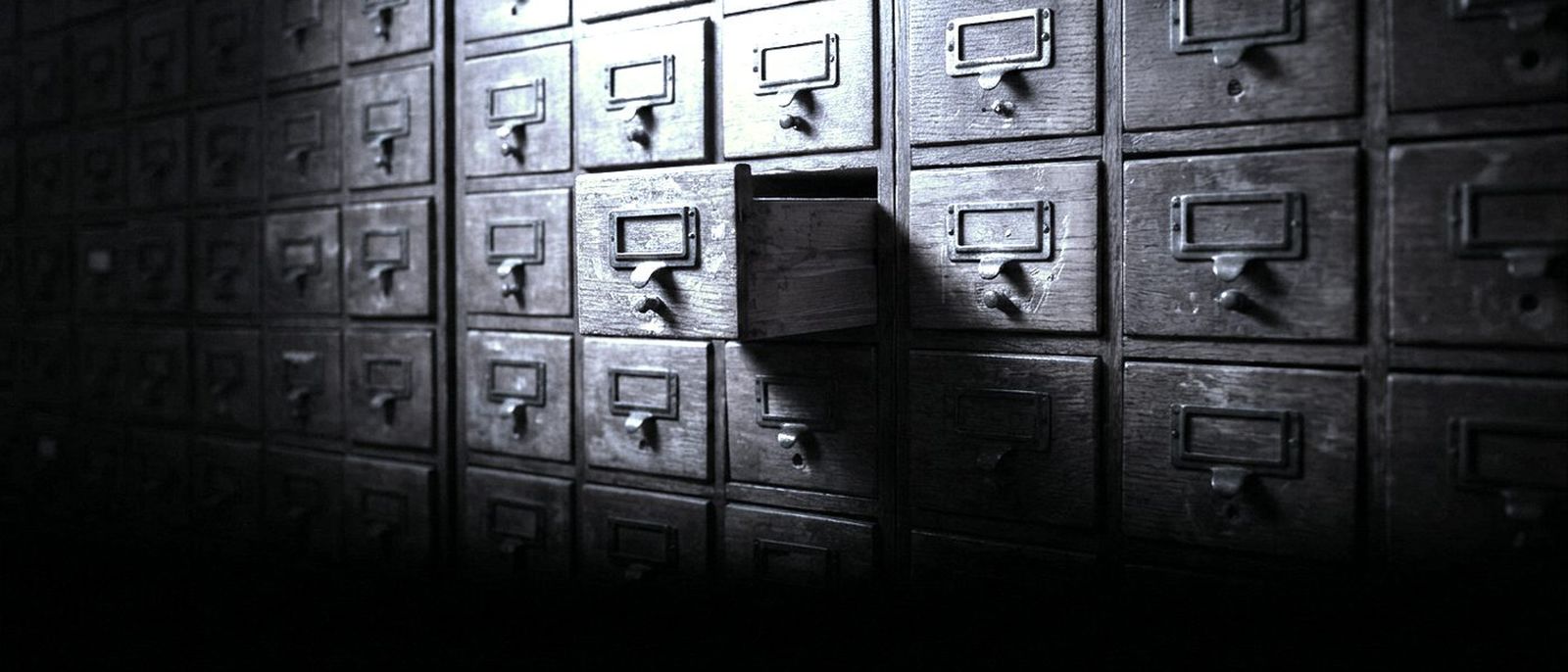 A wall of wooden library card-catalogue drawers, one drawer pulled out.