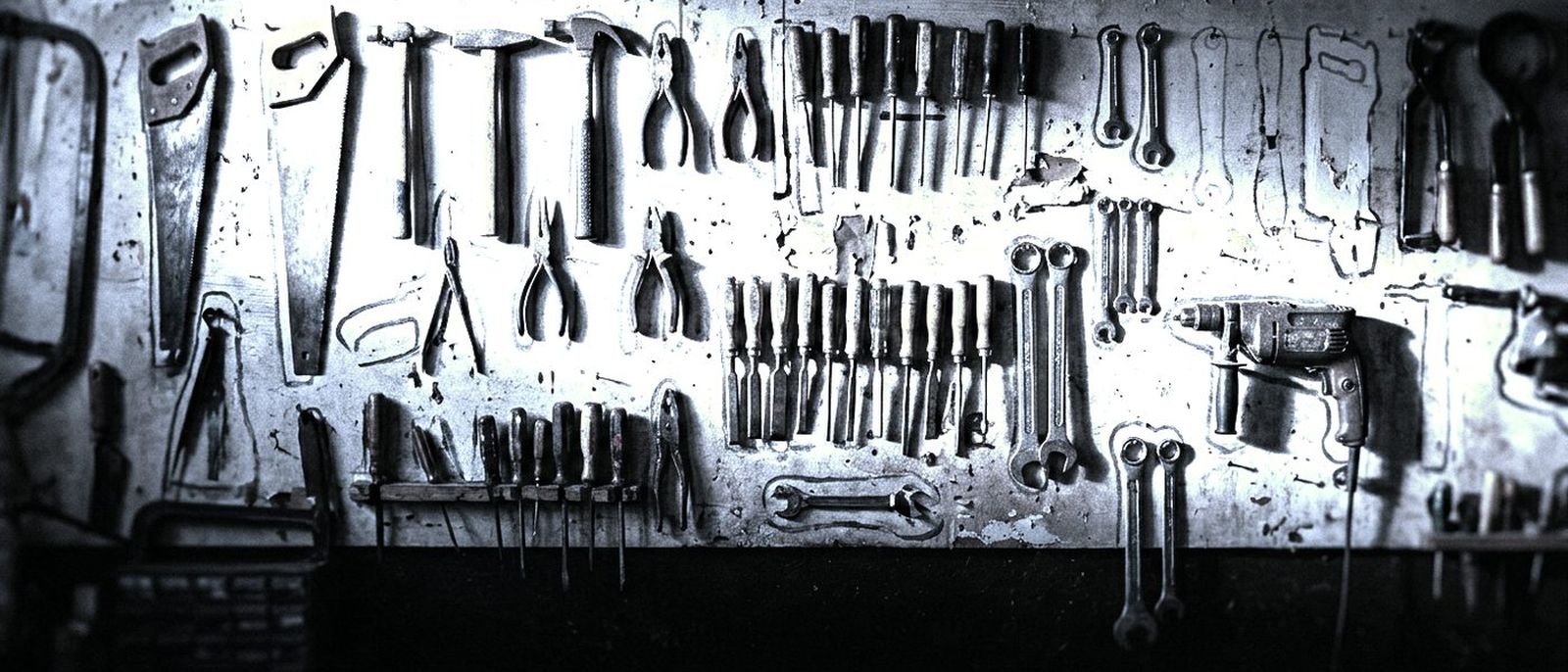 A workshop wall of hand tools, each hung inside its own painted outline.
