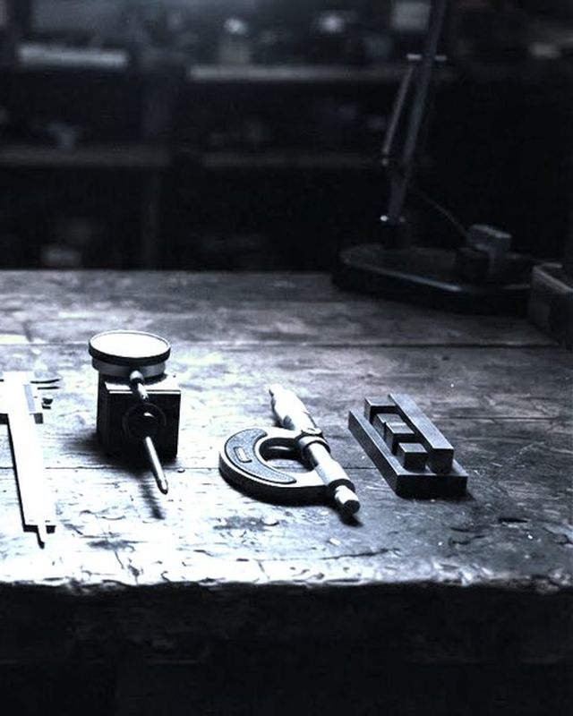 A workbench of precision measuring instruments, calipers and gauges laid out in a row.