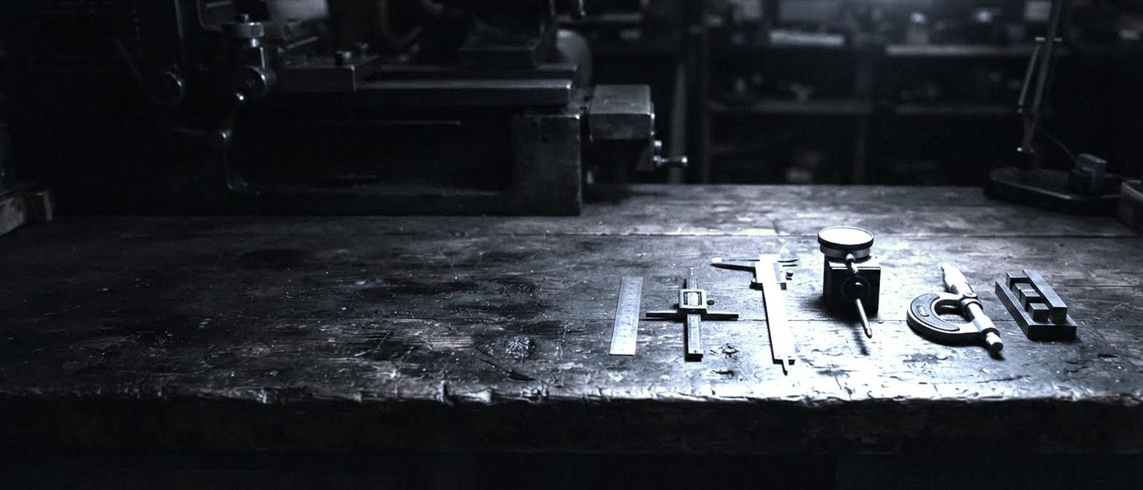 A workbench of precision measuring instruments, calipers and gauges laid out in a row.
