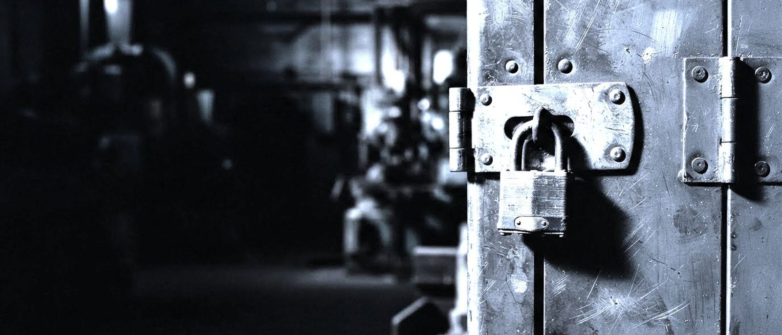 A thick steel hasp and padlock closed on an industrial cabinet door.