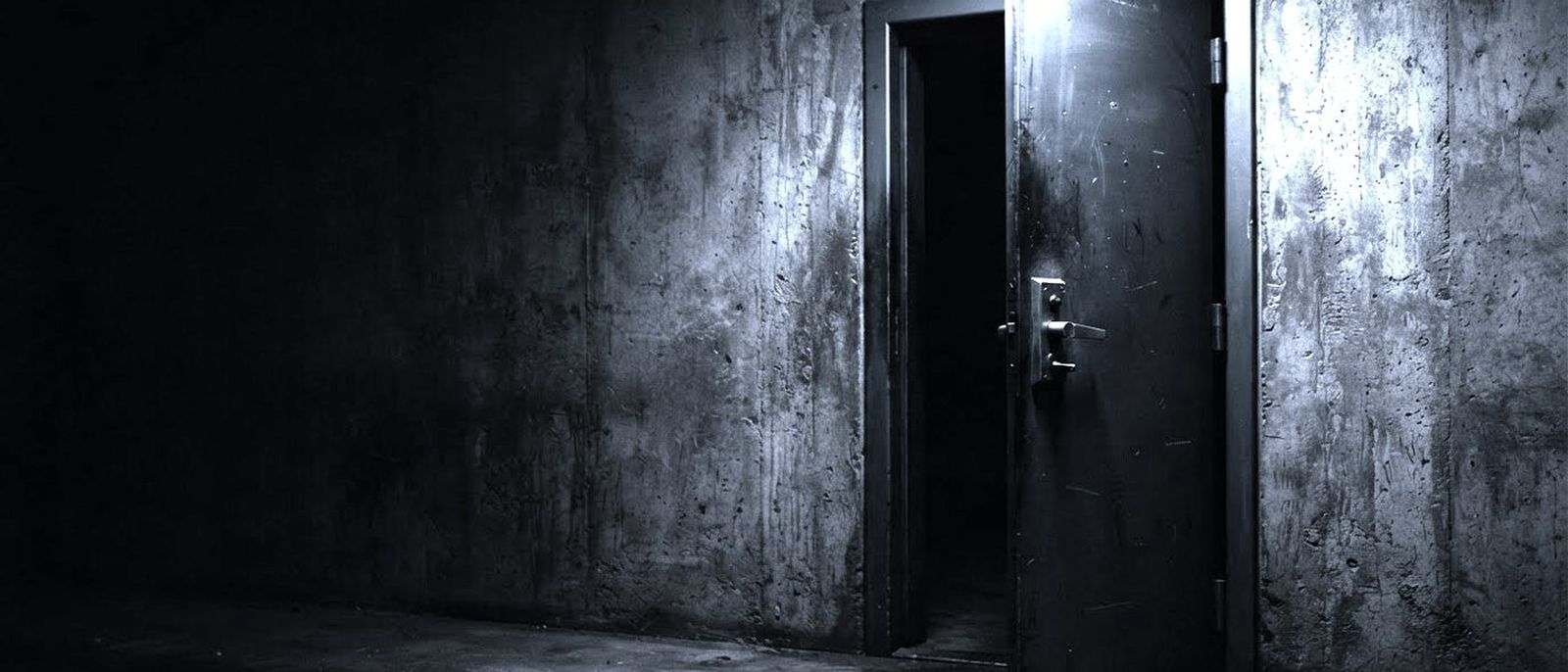 A heavy steel security door with a lever handle, standing slightly open in a concrete wall.