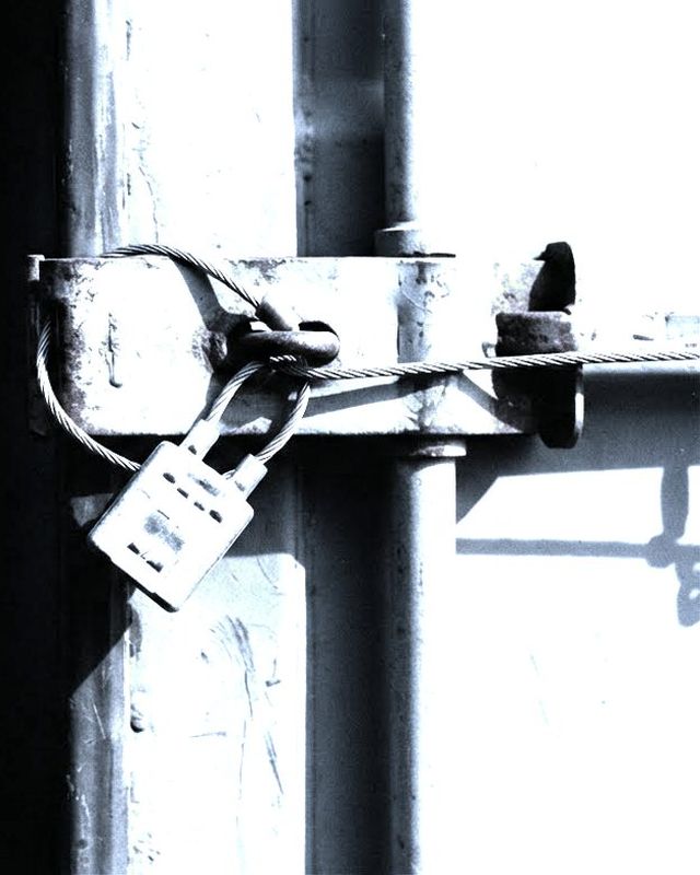 A lead seal crimped onto a steel wire through the hasp of a shipping container door.